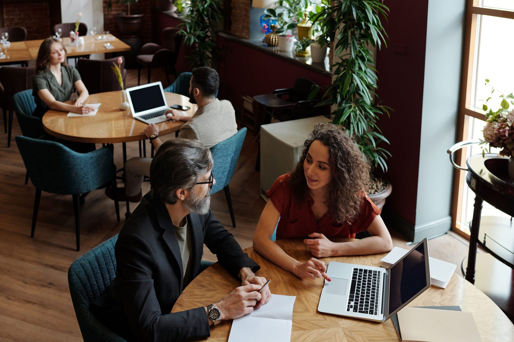 Two people reviewing work together at a cafe table.